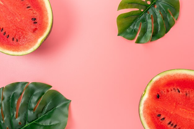 Sandía con hojas de palmera aislado en rosa