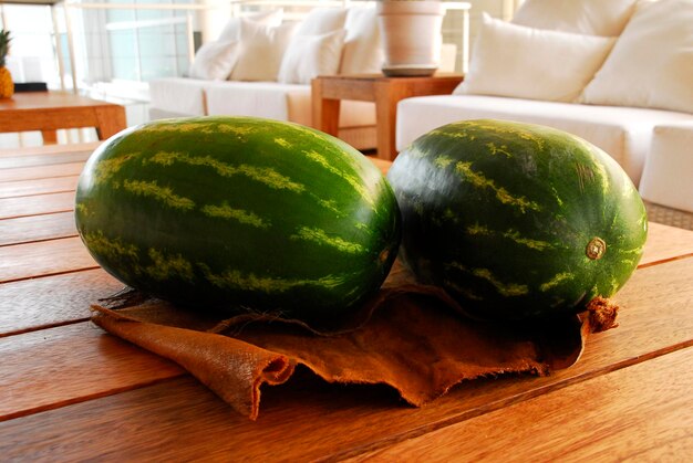 Foto sandía par de sandías verdes sobre una mesa de madera en el interior de una casa comida tropical de frutas