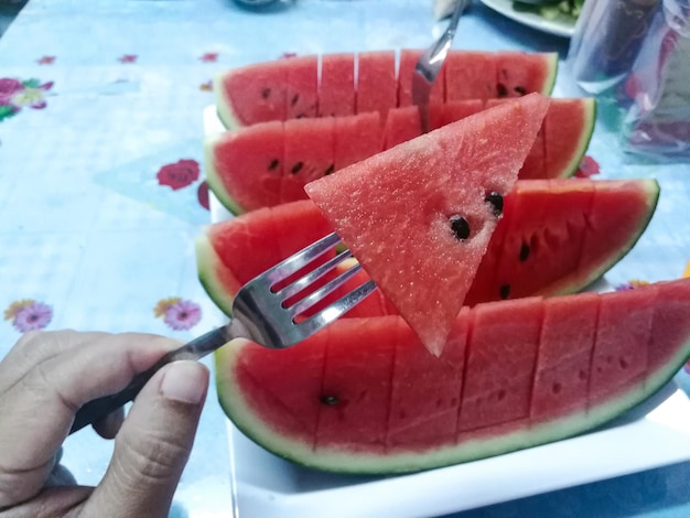 Foto sandía roja cortada en pedazos siendo bifurcada bocadillos de frutas de verano para la frescura