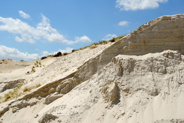 Sandiger Berg aus weißem Sand gegen den blauen Himmel