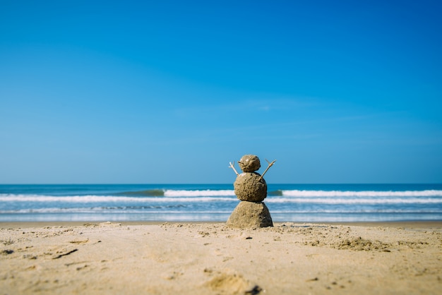 Sandiger glücklicher Mann auf dem Meeresstrand gegen blauen bewölkten Sommerhimmel - Reisekonzept.