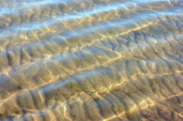 Sandiger Meeresboden durch Wasser und Wellen auf der Oberfläche