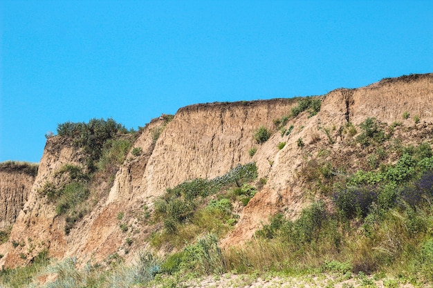 Sandklippe, felsige Berge mit Gras und Büschen bewachsen.