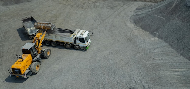 Sandlader schaufeln Steine in Muldenkipper