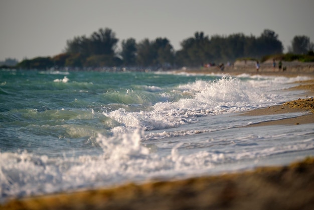 Sandstrand am Meer mit schäumenden Wellen, die an der Küste zermalmen