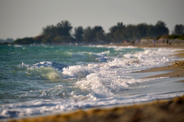 Sandstrand am Meer mit schäumenden Wellen, die an der Küste zermalmen