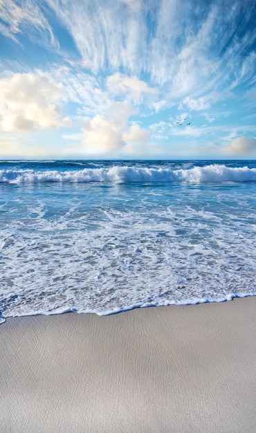 Sandstrand, Meer, blauer Himmel mit Wolken und Kopierraum Szenische Meereslandschaft mit Blick auf Meereswellen, die am Ufer Sand in einem tropischen Resort mit Copyspace waschen. Reisen Sie im Ausland in den Sommerurlaub