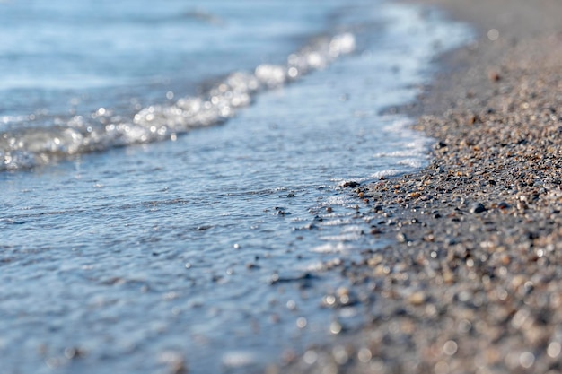 Sandstrand mit kleinen Muscheln vor dem Hintergrund von transparentem Meerwasser