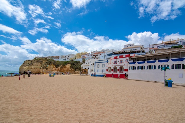 Sandstrand zwischen Klippen und vor charmanter weißer Architektur in Carvoeiro Algarve Portugal