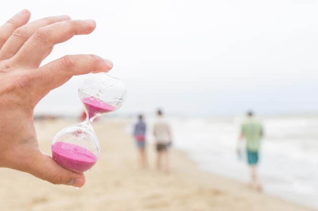 Sanduhr mit rosa Sand in der Hand eines Mannes