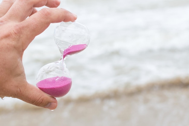 Sanduhr mit rosa Sand in der Hand eines Mannes