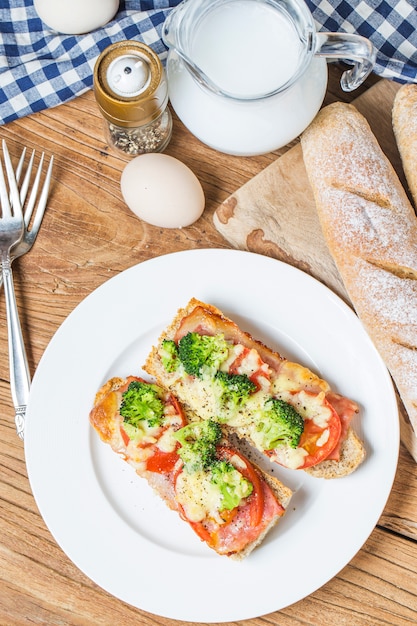 Sanduíche aberto com prosciutto, mozzarella e tomate na mesa da cozinha, foco raso