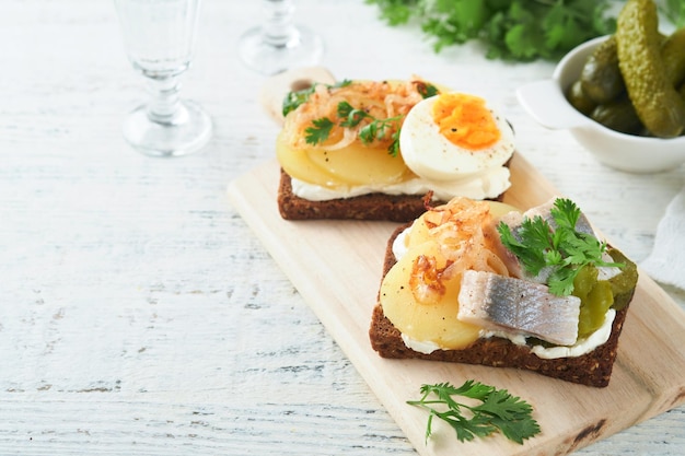 Sanduíche aberto ou smorrebrod com pão de centeio ovos de arenque cebola caramelizada salsa e queijo cottage em fundos de mesa rústica de madeira velha Comida tradicional dinamarquesa ou escandinava lanche almoço