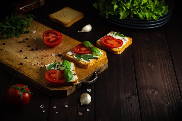 Sanduíche caseiro com salada de cream cheese e tomate em um fundo escuro de madeira com copyspace