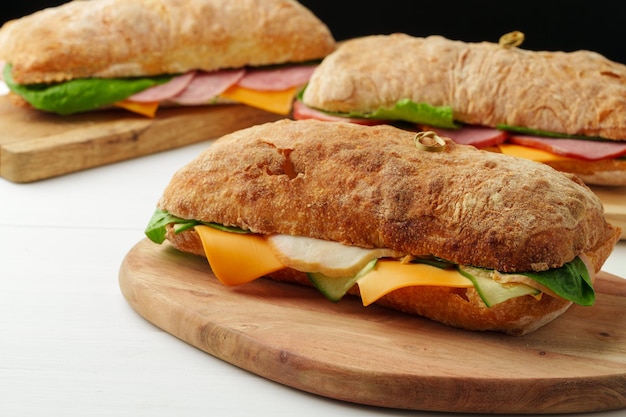 Sanduíche Chiabatta com presunto e queijo na tábua de madeira