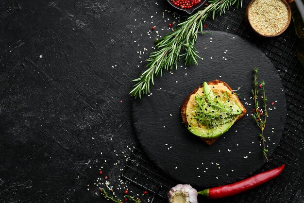 Sanduíche ciabatta abacate hummus e microgreen Café da manhã em uma placa de pedra preta