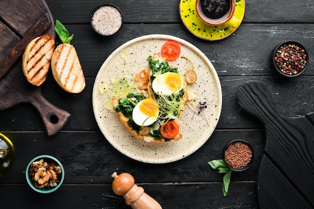 Sanduíche com ovo de espinafre e croissant de tomate Café da manhã no prato Vista superior Composição plana leiga Espaço para cópia gratuita