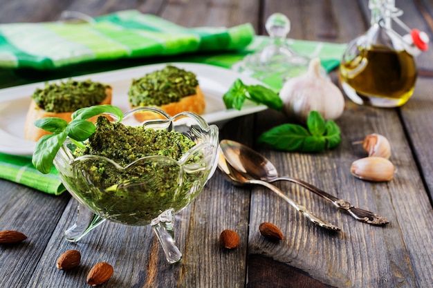 Sanduíche com pesto caseiro, manjericão, azeite e alho em uma velha mesa de madeira. Foco seletivo.