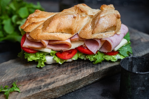 Sanduíche com presunto, queijo, tomate e alface em um fundo escuro