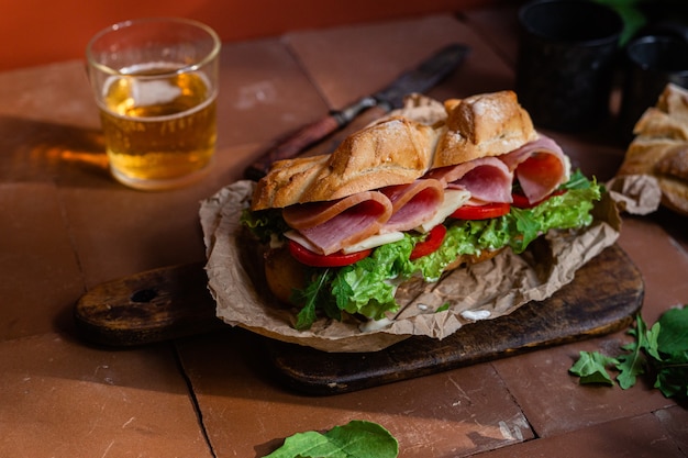 Sanduíche com presunto, queijo, tomate e alface em um fundo escuro