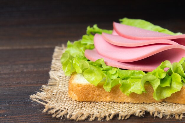 Sanduíche com salsicha fatiada na mesa de madeira