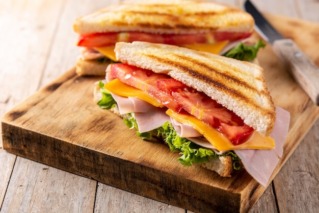 Sanduíche com tomate, alface, presunto e queijo na mesa de madeira