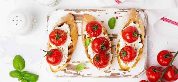 Sanduíche com tomate cereja assado, alho, azeite e requeijão em fundo branco. cozinha italiana. vista do topo.