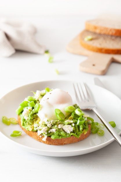 Sanduíche de abacate de café da manhã com ovo escalfado e queijo feta