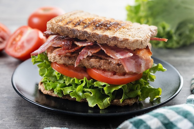 Sanduíche de bacon com alface e tomate em mesa de madeira