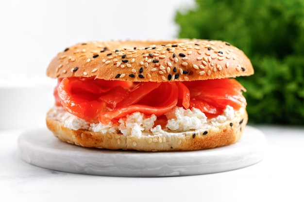 Sanduíche de bagel com cream cheese e salmão na placa de mármore e fundo branco Hambúrguer com salmão
