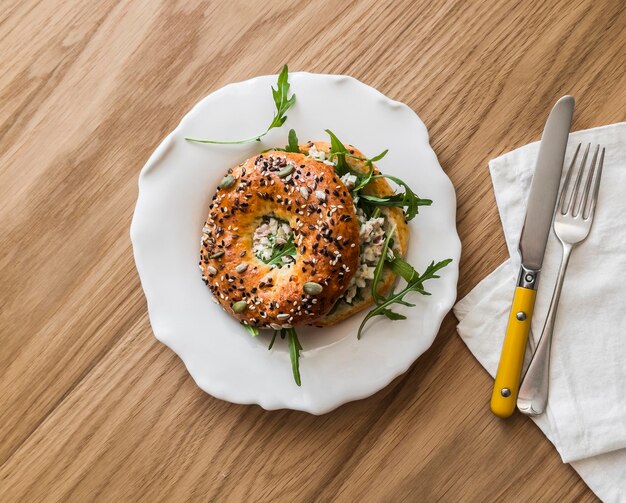 Sanduíche de bagel com salada de ovos de atum e rúcula delicioso lanche de pequeno-almoço em um fundo de madeira vista superior