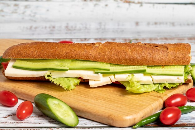 Foto sanduíche de baguete sanduíche com azeitonas alface tomate pepino cheddar e queijo feta em fundo de madeira