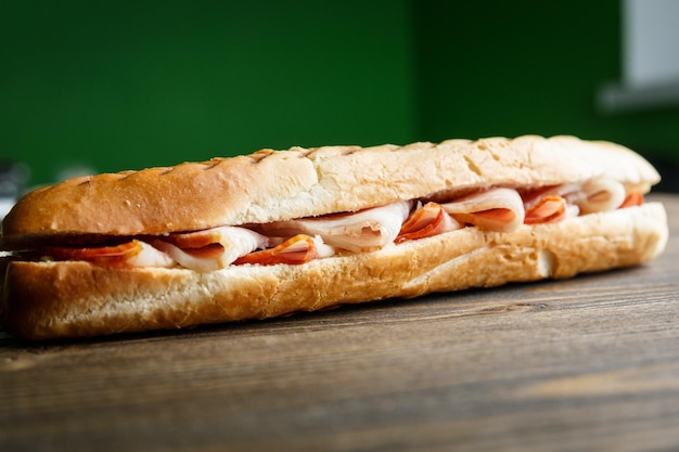 Sanduíche de baguete torrado com presunto em um fundo de madeira