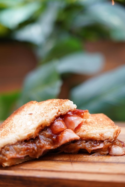 Sanduíche de café da manhã com queijo bacon e molho de tomate na tábua de madeira