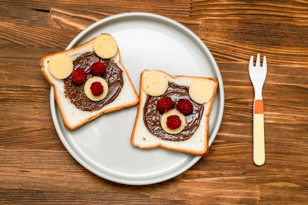 Sanduíche de cara de urso engraçado pão torrado com queijo de manteiga de amendoim e framboesa no prato fundo de madeira Crianças doce sobremesa café da manhã almoço comida close-up