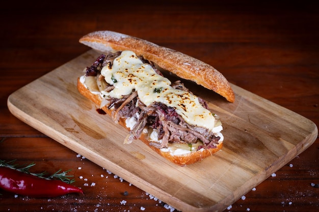 Foto sanduíche de carne picada com molho de mostarda de cebola caramelizada em mesa de madeira almoço delicioso