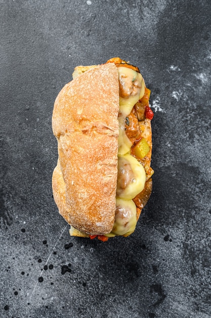 Sanduíche de ciabatta com almôndegas, queijo e molho de tomate. Fundo preto