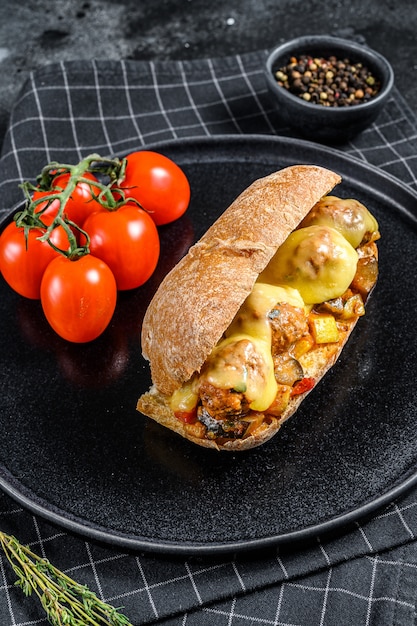 Sanduíche de ciabatta com almôndegas, queijo e molho de tomate. superfície preta. vista do topo