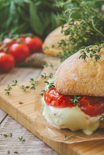 Sanduíche de ciabatta com tomate, ervas e óleo no pão de queijo com alho torrado. tonificado.