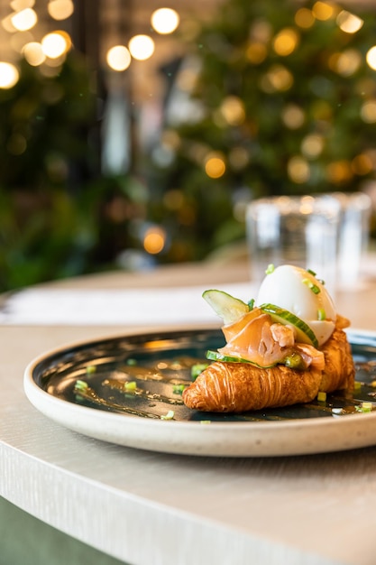 Sanduíche de croissant com ovo escalfado de salmão e pepino Café da manhã no café ou cafeteria Estilos de vida