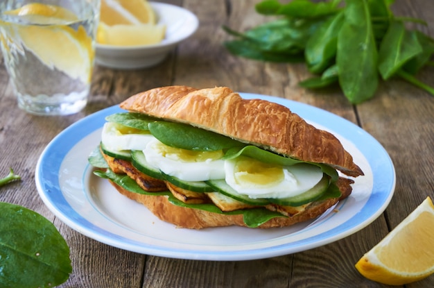 Sanduíche de croissant com ovo, queijo frito e vegetais