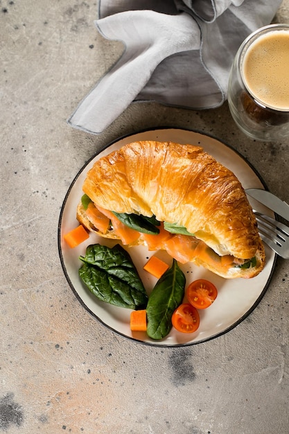 Foto sanduíche de croissant com queijo cottage espinafre de salmão copo de café café da manhã saudável