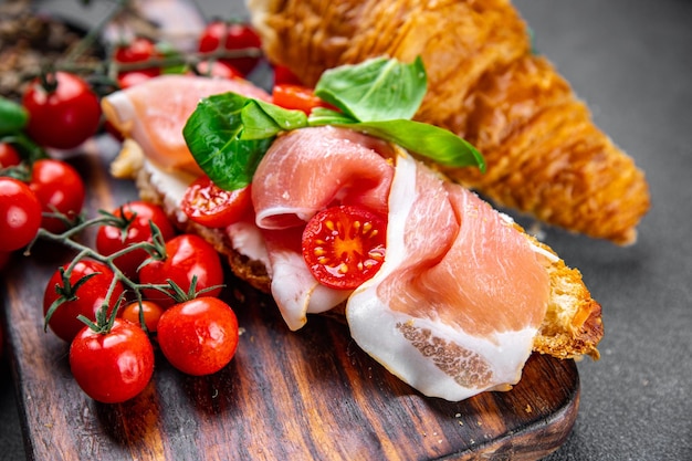 sanduíche de croissant presunto, tomate, salada de folhas verdes fast food refeição saudável para viagem lanche