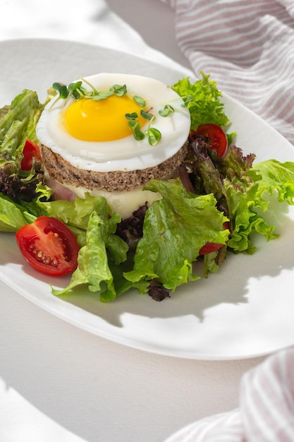 Sanduíche de croque com presunto de queijo e ovo em um prato sobre uma mesa leve Café da manhã caseiro saudável