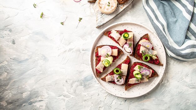 Sanduíche de filé de arenque com fatia de arenque salgado beterraba pepino verde cebola e microgreen nas torradas Cozinha escandinava Tradição Sanduíche aberto dinamarquês vista superior