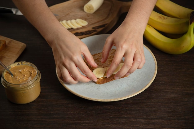 Sanduíche de manteiga de amendoim com banana Uma mulher a preparar o pequeno-almoço