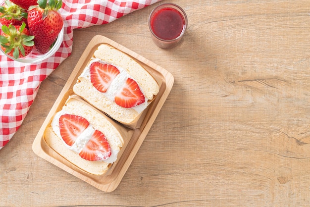 sanduíche de panqueca com creme de morango fresco no prato de madeira