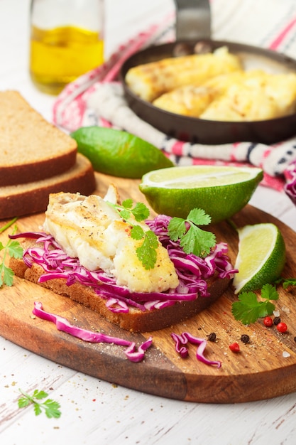 Sanduíche de pão de centeio, peixe branco assado e salada de repolho roxo