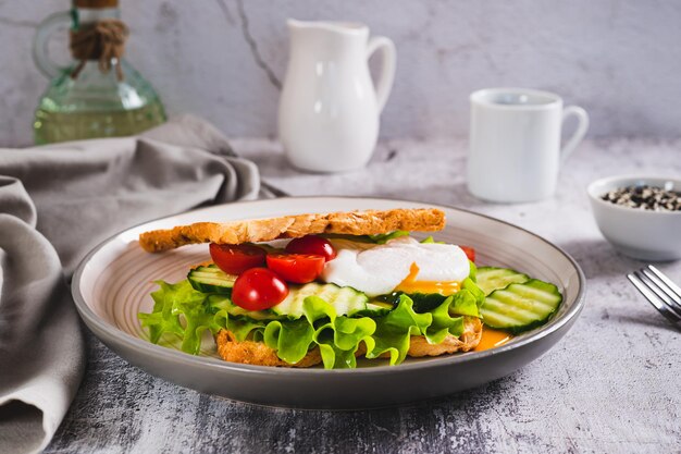 Foto sanduíche de pão de waffle com ovo cozido e legumes em um prato na mesa