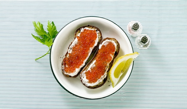 Sanduíche de pão fresco com caviar vermelho e queijo em um prato. combinação clássica de ingredientes.